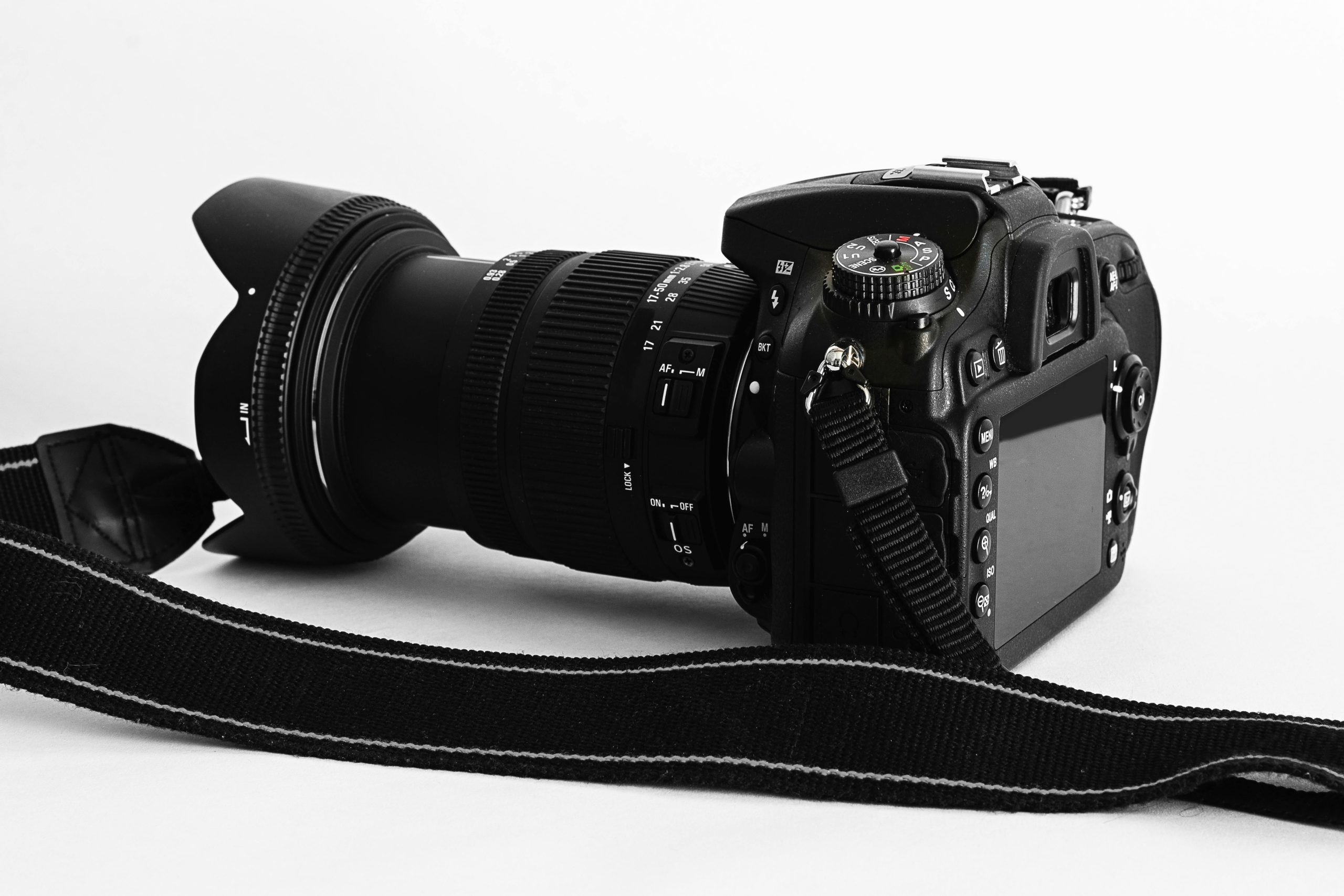 Close-up of a DSLR camera with lens and strap on a white background.